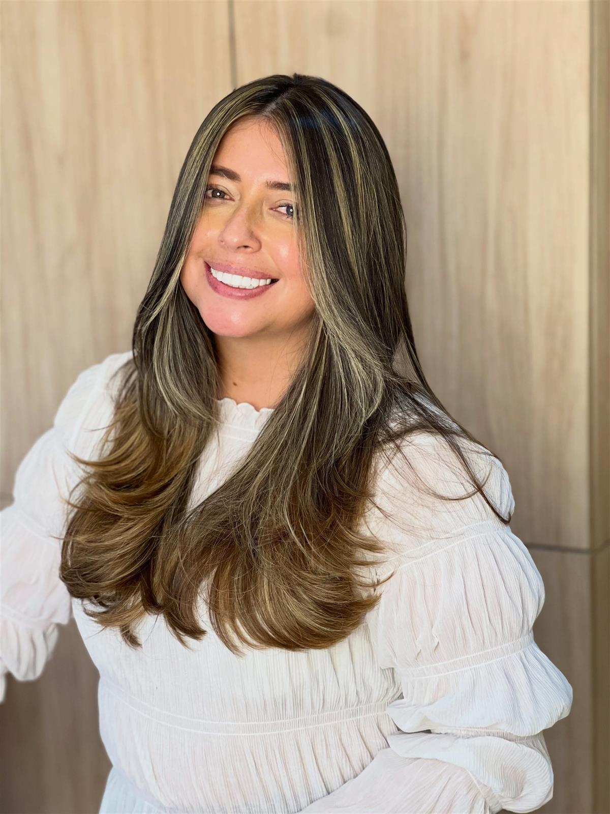 Clienta sonriente con mechas caramelo que enmarcan el rostro